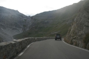 Klikatící se silnice zaříznutá v prudkém svahu hory Dreisprachenspitze - uprostřed nahoře Passo Stelvio